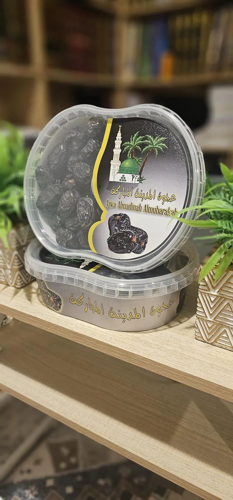 Twee bakjes Ajwa-dadels uit Madinah van onze eigen lijn, op een houten plank