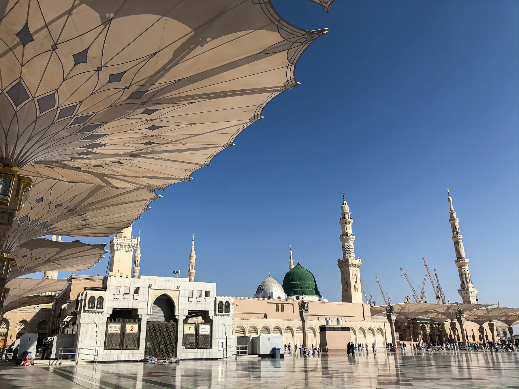 De parasols van Masjid an-Nabawi met de groene koepel en minaretten tegen een blauwe lucht
