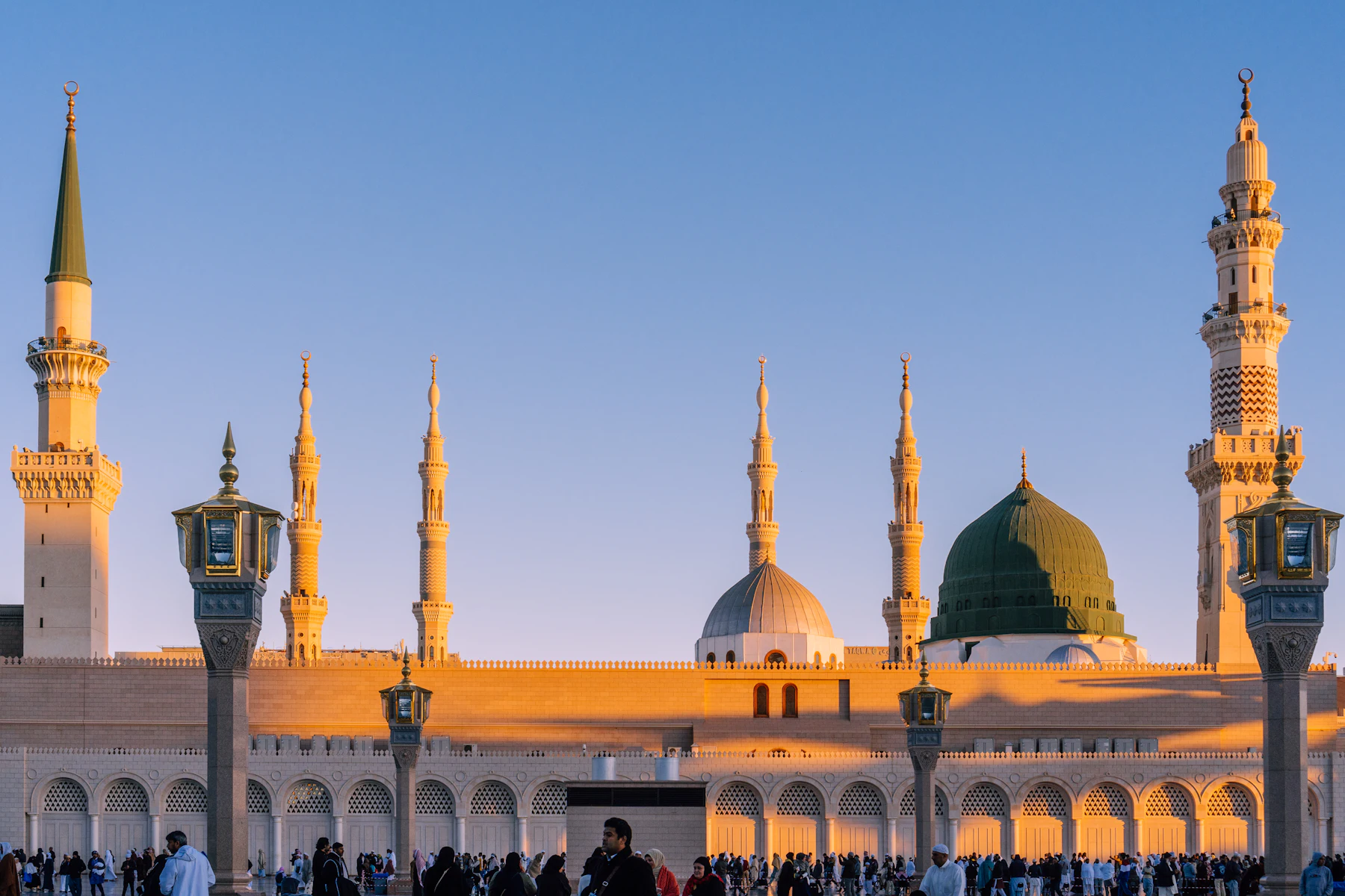 Masjid an-Nabawi in het warme licht van de vroege ochtend, met bezoekers op het plein