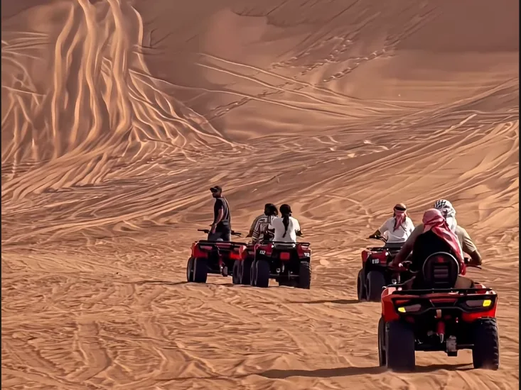 Een groep rijdt op rode quads door de zandduinen